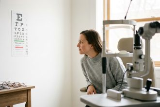 Femme passant un contrôle de la vue chez un ophtalmologue, lisant un tableau optométrique dans un cabinet moderne