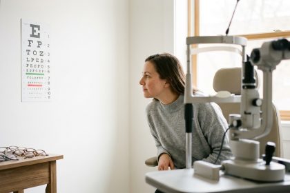 Femme passant un contrôle de la vue chez un ophtalmologue, lisant un tableau optométrique dans un cabinet moderne