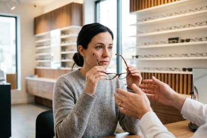 Femme essayant des lunettes dans un magasin d'optique moderne avec un opticien conseil
