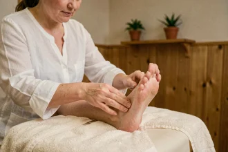 Thérapeute pratiquant la réflexologie plantaire sur le pied d'une cliente dans un studio de bien-être
